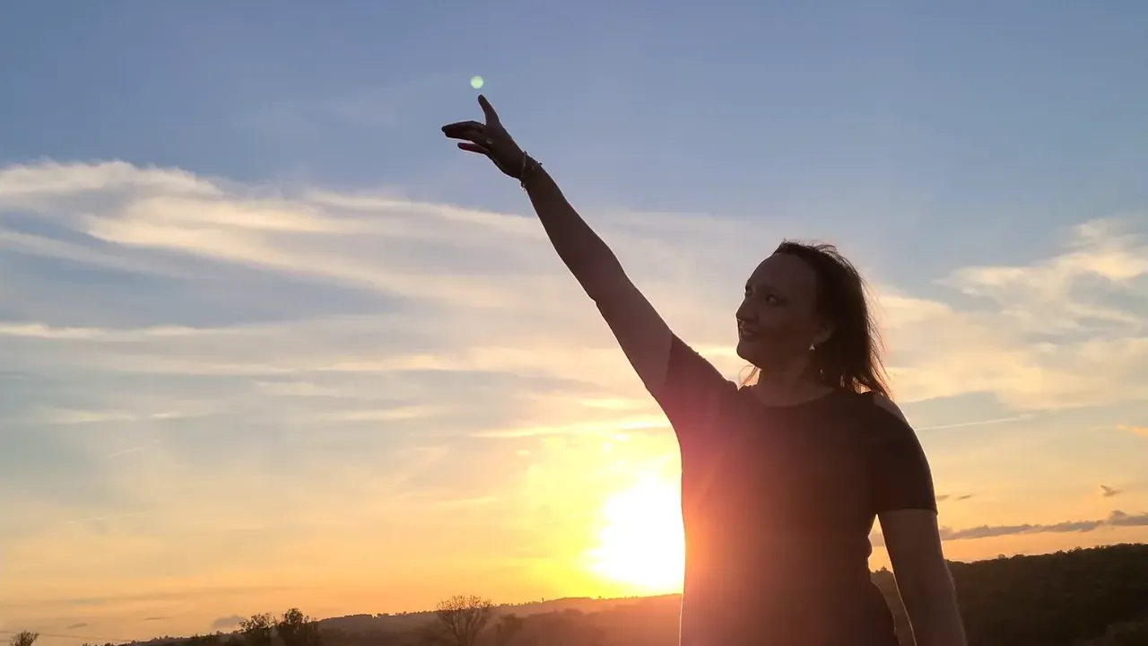 Hilbi en contre-jour, le bras tendu vers le soleil couchant